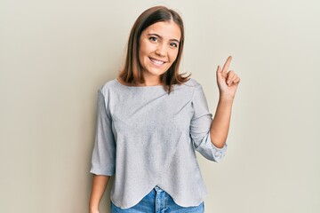 Poster - Young beautiful woman wearing casual clothes smiling with an idea or question pointing finger up with happy face, number one