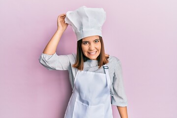 Canvas Print - Young beautiful woman wearing professional cook uniform and hat confuse and wonder about question. uncertain with doubt, thinking with hand on head. pensive concept.