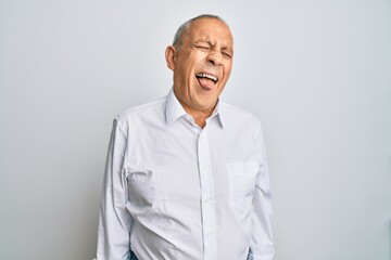 Canvas Print - Handsome senior man wearing casual white shirt sticking tongue out happy with funny expression. emotion concept.