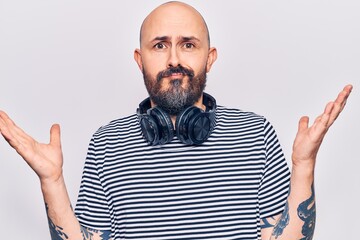 Poster - Young handsome man listening to music using headphones clueless and confused with open arms, no idea and doubtful face.