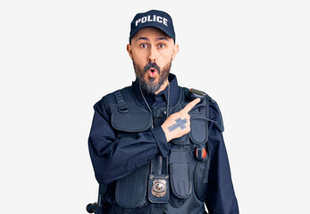 Poster - Young handsome man wearing police uniform surprised pointing with finger to the side, open mouth amazed expression.