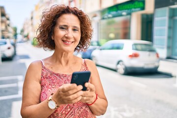 Poster - Middle age woman smiling happy using smartphone walking at street of city.