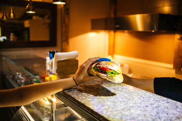 Wall Mural - Selective focus shot of a person holding a tasty sandwic