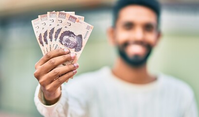 Poster - Young african american man smiling happy holding mexican 500 pesos banknotes at the city.