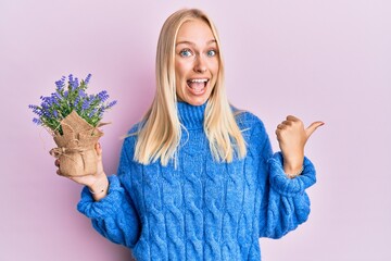 Sticker - Young blonde girl holding lavender pot pointing thumb up to the side smiling happy with open mouth