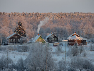 Wall Mural - View of a village in the Republic of Karelia on a sunny frosty day, smoke from the chimney above the house