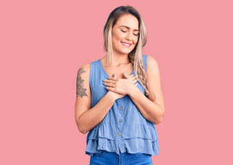 Sticker - Young beautiful blonde woman wearing casual sleeveless t-shirt smiling with hands on chest with closed eyes and grateful gesture on face. health concept.