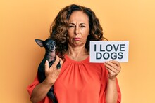 Middle Age Hispanic Woman Holding Chihuahua Dog And Paper With I Love Dogs Phrase Skeptic And Nervous, Frowning Upset Because Of Problem. Negative Person.