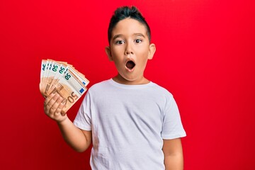 Sticker - Little boy hispanic kid holding bunch of 50 euro banknotes scared and amazed with open mouth for surprise, disbelief face