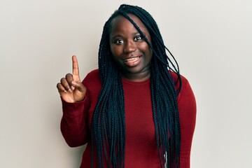 Sticker - Young black woman with braids wearing casual clothes smiling with an idea or question pointing finger up with happy face, number one