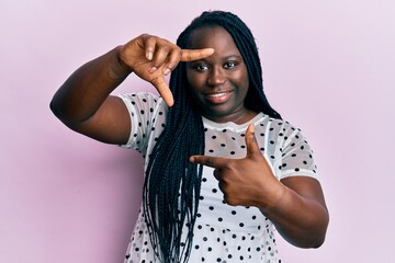 Sticker - Young black woman with braids wearing casual clothes smiling making frame with hands and fingers with happy face. creativity and photography concept.