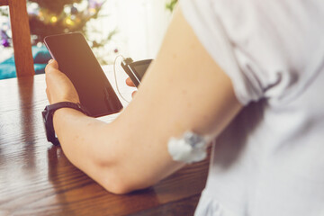 Sticker - Modern diabetes treatment, woman checking glucose level and dosing insulin using insulin pump and remote sensor on her hand, focus on background