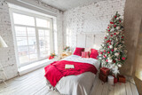 Fototapeta  - A spacious white light bedroom in a loft style with a decorated Christmas tree and a garland.