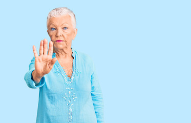 Wall Mural - Senior beautiful woman with blue eyes and grey hair wearing summer dress doing stop sing with palm of the hand. warning expression with negative and serious gesture on the face.