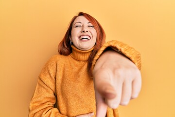 Sticker - Beautiful redhead woman wearing casual winter sweater over yellow background laughing at you, pointing finger to the camera with hand over body, shame expression