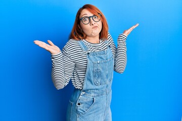 Poster - Beautiful redhead woman wearing casual clothes and glasses clueless and confused with open arms, no idea and doubtful face.