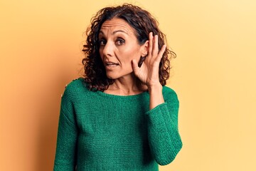 Canvas Print - Middle age beautiful woman wearing casual sweater smiling with hand over ear listening and hearing to rumor or gossip. deafness concept.