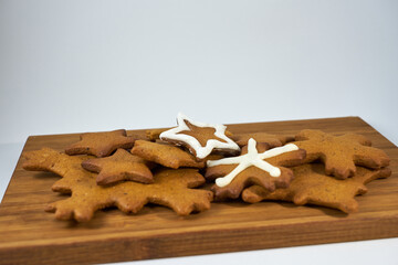 Ginger biscuits with sugar powder on a wooden board on a white background.