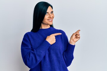 Young caucasian woman wearing casual clothes smiling and looking at the camera pointing with two hands and fingers to the side.