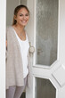© MrsLePew - Cheerful young woman welcome friends at open front door
