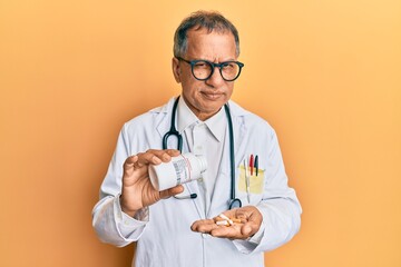 Poster - Middle age indian man wearing doctor uniform holding prescription pills skeptic and nervous, frowning upset because of problem. negative person.