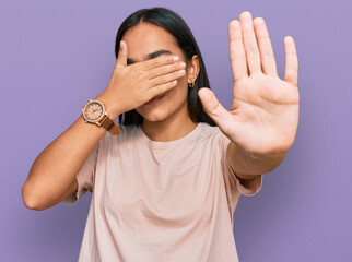 Wall Mural - Young asian woman wearing casual clothes covering eyes with hands and doing stop gesture with sad and fear expression. embarrassed and negative concept.