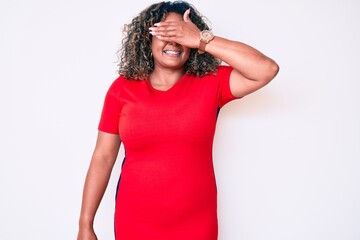 Wall Mural - Young african american plus size woman wearing casual clothes smiling and laughing with hand on face covering eyes for surprise. blind concept.