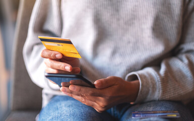 Wall Mural - Closeup image of a woman using credit card for purchasing and shopping online on mobile phone