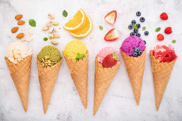 Fototapete - Various of ice cream flavor in cones blueberry ,pistachio ,almond ,orange and cherry setup on white stone background . Summer and Sweet menu concept.