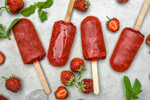 Homemade popsicles with strawberries, ice lollies on sticks, top view, flat lay