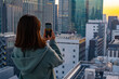 高層ビルの夕景を撮影する女性