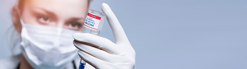  Doctor holding a syringe with a single bottle vial of Covid-19 vaccine and she is ready for vaccination. Close up. Medical concept vaccination hypodermic injection treatment.  Copy space for text.