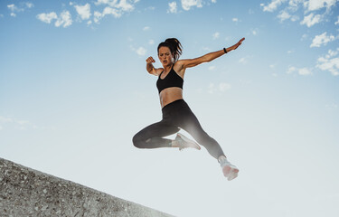 Wall Mural - Fitness woman jumping from wall