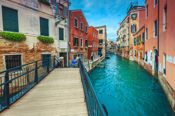  Water canal with bridges and old buildings in Venice, Italy