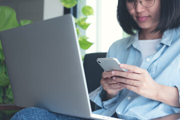 Sticker - Young asian casual business woman using mobile phone and online working on laptop computer in coffee shop