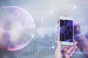 Double exposure of forex graph sketch hologram and woman holding and using a mobile device. Stock market concept.