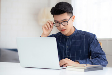 Wall Mural - Young business man in glasses working from home with laptop computer on desk, freelance male sitting stay home using notebook for communication on table, entrepreneur in startup business, new normal.