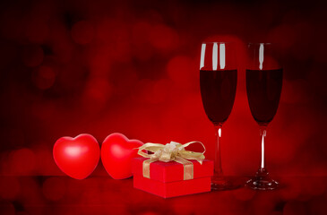 Wall Mural - Two wineglasses and red gift box and heart shape on desk with red blur bokeh background, champagne glasses and presents with celebration and anniversary, love and romantic, valentine day concept.