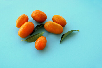 Wall Mural - Fresh kumquat fruits on blue background, top view, winter fruits