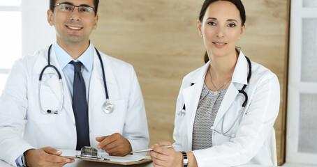 Two doctors discussing treatment problems while sitting at the desk in hospital office. Data in medicine and health care concept