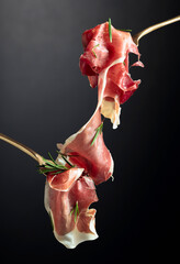 Wall Mural - Sliced prosciutto with rosemary on forks.