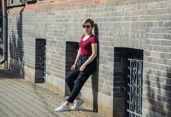 Wall Mural - A girl stands against a red brick wall