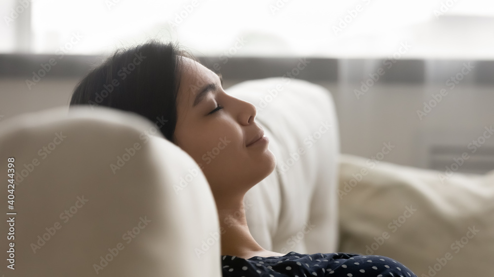 Close up head shot happy serene millennial asian mixed race woman leaning on comfortable sofa, daydreaming sleeping napping restoring energy, enjoying tranquil peaceful weekend time at home. - obrazy, fototapety, plakaty 