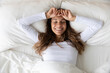 © fizkes - Top view from above smiling young woman stretching, lying in comfortable bed after awakening, happy positive young female wearing pajama resting on soft pillows under warm blanket, enjoying morning