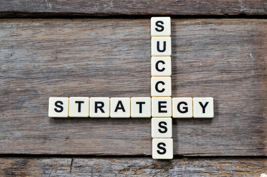Top view of scrabble letters with text SUCCESS and STRATEGY over wooden background. Business and education concept. 