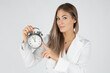 © MrsLePew - young female businesswoman demonstrating alarm clock showing almost midnight time while standing against white background