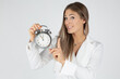 © MrsLePew - young female businesswoman demonstrating alarm clock showing almost midnight time while standing against white background