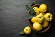 Fresh ripe organic quinces with leaves on black table, flat lay. Space for text