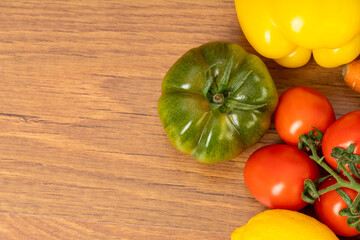 Wall Mural - Brown wooden background with green tomato, red cherry tomatoes and peppers