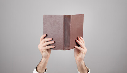 Wall Mural - Male hands holding book on grey background.